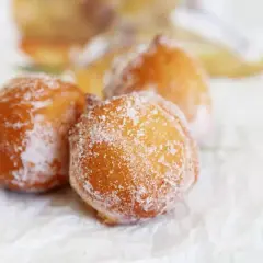 Trois beignets dorés, saupoudrés de sucre, évoquant un délicieux dessert de Côte d'Ivoire.