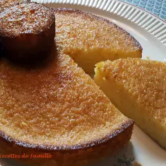 Un délicieux gâteau à l'orange, avec une croûte dorée et une mie moelleuse, servi sur une assiette blanche.
