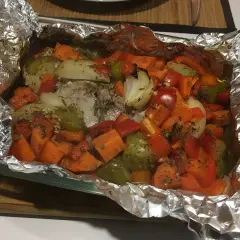 Filet mignon en papillote aluminium, cuit avec des légumes colorés comme des carottes, poivrons et oignons. Un plat savoureux et sain.