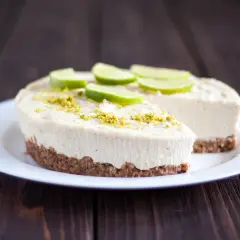 Un délicieux gâteau zéphyr crémeux, garni de fines tranches de citron vert et de zestes, sur une assiette blanche.
