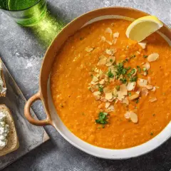 Soupe égyptienne onctueuse, garnie d'amandes effilées et de persil frais, avec une tranche de citron. Accompagnée de toasts au fromage frais.