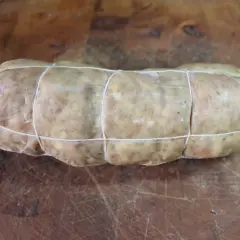 Un sabodet à la vigneronne, charcuterie artisanale ficelée, prête à être cuisinée sur une planche en bois.