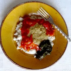 Un plat guinéen facile : riz blanc, sauce verte, sauce tomate et feuilles de manioc sur une assiette jaune.