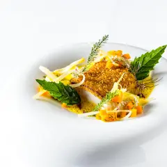 Un plat de silure pané, servi avec des dés de courge, des herbes fraîches et une sauce légère. Une belle présentation pour une recette de silure au court bouillon.