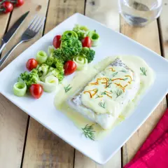 Dos de cabillaud au four, nappé d'une sauce onctueuse au vin blanc et crème fraîche, accompagné de brocolis, tomates cerises et rouleaux de concombre.