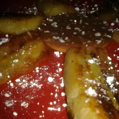 Délicieuse banane grillée à la poêle, saupoudrée de sucre glace, sur une assiette rouge. Un dessert gourmand et simple.