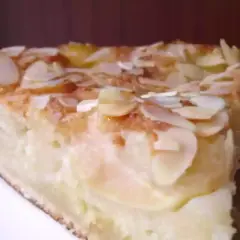 Une part de gâteau d'Ève, aux pommes et amandes effilées, dorée et appétissante.