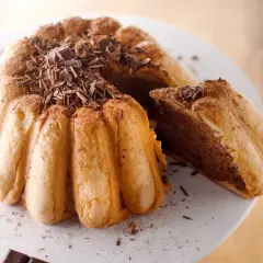 Une délicieuse charlotte malakoff au chocolat, garnie de copeaux de chocolat noir et saupoudrée de cacao.