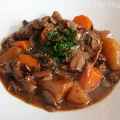 Un savoureux bourguignon végétarien avec des champignons, des carottes et des pommes de terre, garni de persil frais.