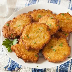Assiette de beignets de brimbelle dorés, parsemés de persil frais. Un délice croustillant !
