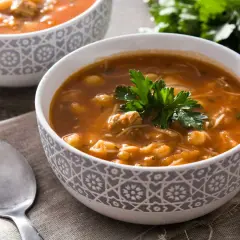 Un bol de recette harira berbère, une soupe réconfortante aux pois chiches, viande et vermicelles, garnie de persil frais.