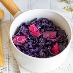 Un bol de chou rouge cuit, parsemé de morceaux de pomme, prêt à être dégusté. Une recette simple et savoureuse.