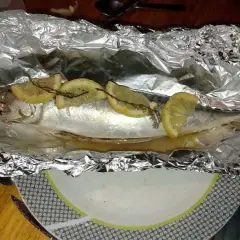 Maquereau entier, prêt à être cuit en papillote au barbecue, garni de rondelles de citron et d'herbes.