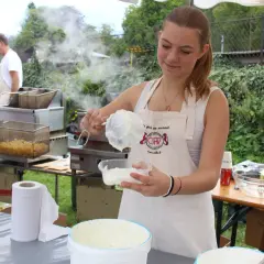 Une jeune femme prépare une recette chique de sauce crémeuse. Derrière elle, des frites dorent dans une friteuse.