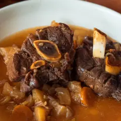 Un plat réconfortant de jarret de cerf mijoté avec des carottes et des pommes de terre dans un bouillon savoureux.