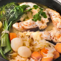 Un plat appétissant de daube de congre, avec des morceaux de poisson tendres, des pommes de terre, des carottes et des poireaux, le tout mijoté dans un bouillon savoureux.