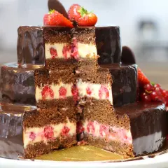 Gâteau à trois étages, chocolaté et garni de framboises, décoré de fraises et de groseilles. Un délice pour les yeux et les papilles, ce gâteau Christine est une œuvre d'art.