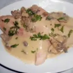 Délicieux jambon braisé au cidre, nappé d'une sauce crémeuse aux champignons et parsemé de persil frais. Un plat réconfortant.