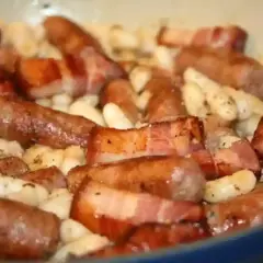 Saucisses catalanes enveloppées de lard, mijotant avec des haricots blancs. Une recette savoureuse à découvrir.