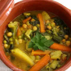 Un savoureux tajine végétarien aux carottes, pois chiches, pommes de terre et courgettes, garni de persil frais.