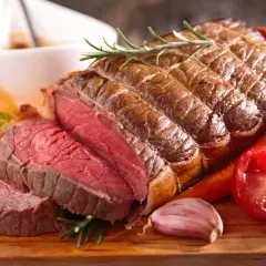 Un rôti de bœuf saignant, garni de romarin, carottes et ail. Une recette parfaite pour un repas de fête.