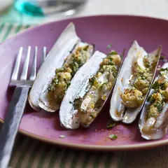 Couteaux cuisinés, une recette de chapeau chinois coquillage, servis sur une assiette rose avec une fourchette.