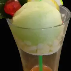 Un trou normand rafraîchissant avec une boule de glace vanille, des morceaux de fruits et une cerise.