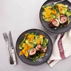 Deux assiettes de involtini de boeuf avec une salade de courgettes et carottes en rubans. Un repas léger et coloré.