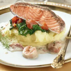 Filet de saumon sur purée, garni d'épinards et tomates, nappé d'une délicieuse sauce crevette. Un plat savoureux.