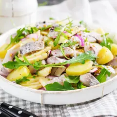 Salade de pommes de terre et hareng frais à la poêle, garnie de roquette et d'oignons rouges. Une recette simple et savoureuse.