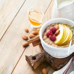 Délicieuse bouillie bretonne garnie de fruits rouges, poire et amandes, avec du miel et du lait à côté.