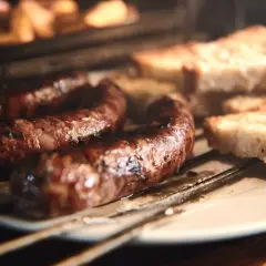 Figatelli grillés au four, accompagnés de tranches de pain rustique. Une recette simple et savoureuse.