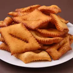 Une assiette de bugnes au four dorées et croustillantes, prêtes à être dégustées.