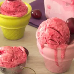 Trois coupes colorées servent une délicieuse recette sorbet cerise, avec des cerises fraîches et une cuillère à glace.