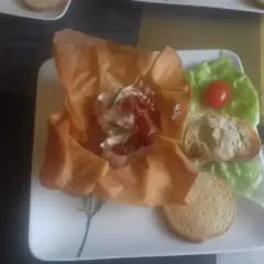 Une délicieuse grolle recette : une coupe de pâte filo garnie de fromage frais, tomates séchées et ciboulette, servie avec des toasts et une feuille de laitue.