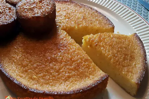 Un délicieux gâteau à l'orange, avec une croûte dorée et une mie moelleuse, servi sur une assiette blanche.