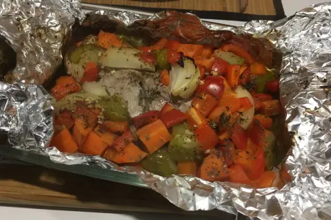 Filet mignon en papillote aluminium, cuit avec des légumes colorés comme des carottes, poivrons et oignons. Un plat savoureux et sain.