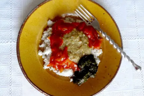 Un plat guinéen facile : riz blanc, sauce verte, sauce tomate et feuilles de manioc sur une assiette jaune.