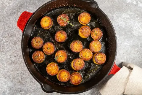 Pommes de terre en sauce brune, dorées et savoureuses, mijotent dans une poêle en fonte avec des herbes aromatiques.