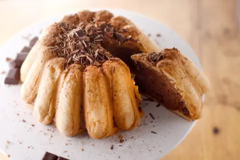 Une délicieuse charlotte malakoff au chocolat, garnie de copeaux de chocolat noir et saupoudrée de cacao.