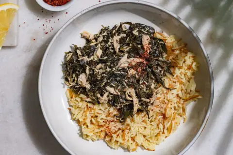 Un plat de mloukhia libanais avec du riz aux vermicelles, garni de poulet effiloché et d'épices rouges.