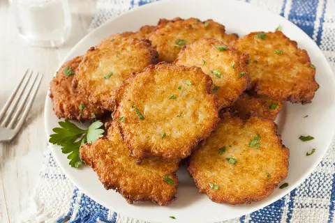 Assiette de beignets de brimbelle dorés, parsemés de persil frais. Un délice croustillant !