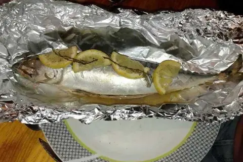 Maquereau entier, prêt à être cuit en papillote au barbecue, garni de rondelles de citron et d'herbes.