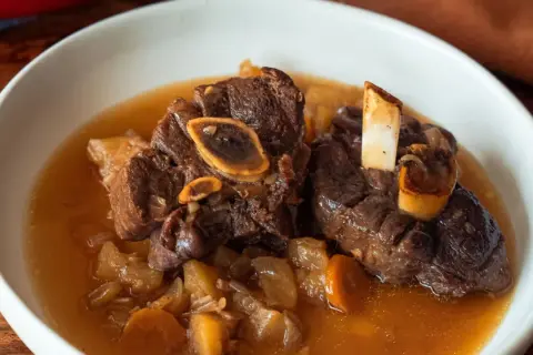 Un plat réconfortant de jarret de cerf mijoté avec des carottes et des pommes de terre dans un bouillon savoureux.