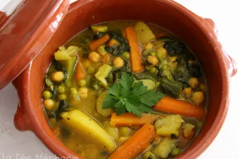 Un savoureux tajine végétarien aux carottes, pois chiches, pommes de terre et courgettes, garni de persil frais.