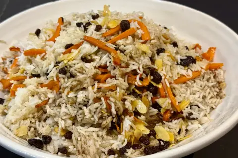 Un plat de riz parfumé, garni de carottes râpées, de raisins secs et d'amandes effilées. Une belle présentation de la recette riz afghan.