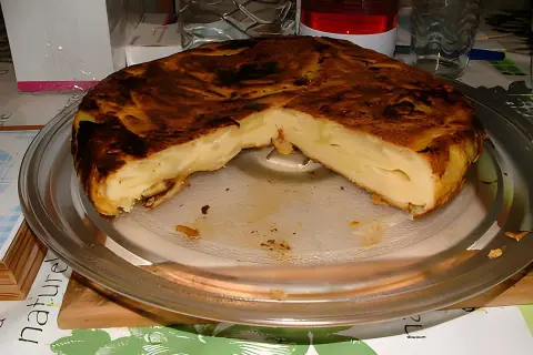 Une délicieuse farinette aux pommes, dorée et moelleuse, servie sur un plat en verre. Un vrai régal !