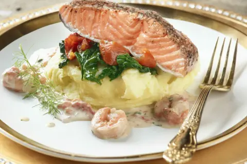 Filet de saumon sur purée, garni d'épinards et tomates, nappé d'une délicieuse sauce crevette. Un plat savoureux.