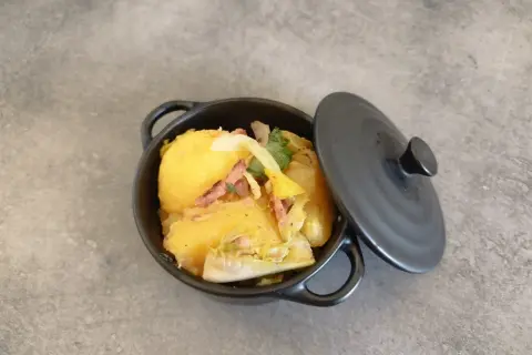Un plat de pommes de terre et lardons, rappelant la recette ardennaise de nos grands-mères, servi dans une cocotte noire.