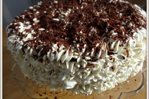 Gâteau noir en chemise de crème fouettée et copeaux de chocolat.
